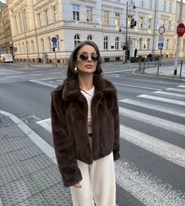 Detail of dark brown faux fur jacket with lapels shown in an urban street setting