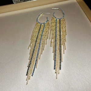 Detail of gold tassel earrings with blue rhinestones and long chain fringe