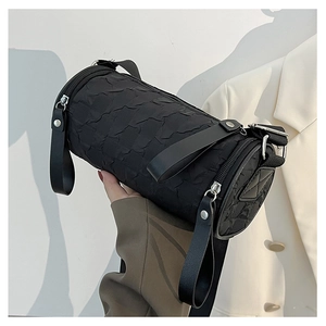 Close-up of a black textured cylinder bag with double zipper and bubble fabric detail