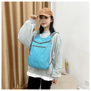 Sky blue foldable travel backpack front view on model with water-resistant nylon texture