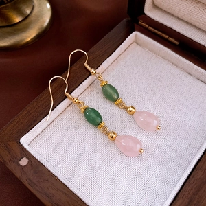 Detail of water drop fringe earrings with pink and green beads on vintage wooden box