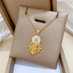 Close-up of a gold Virgin Mary pendant with rose details on a white shell base