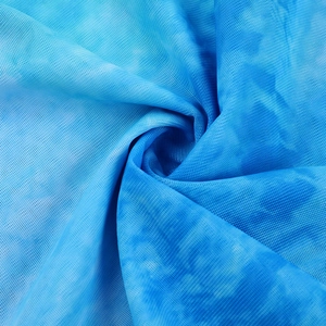 Macro view of blue tie-dye mesh fabric showing spiral pleated texture and mesh weave