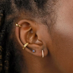 Gros plan sur des manchettes d'oreille dorées et une puce en zircon bleu saphir