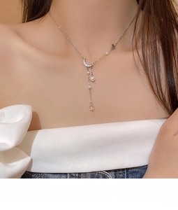 Macro view of silver necklace showing pearl moon pendant and butterfly charm details