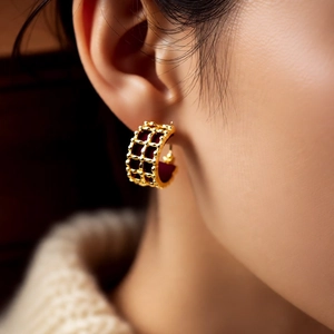 Close-up of model wearing 18K gold plated grid earrings with burgundy leather inlay