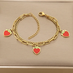 Detail of double-layer gold titanium bracelet with red strawberry enamel pendants
