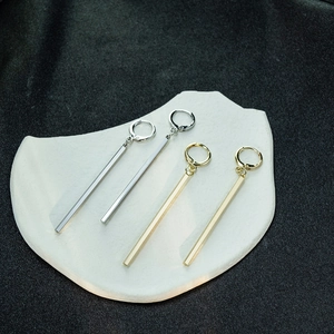 Detailed view of gold and silver geometric bar drop earrings on a white stone tray
