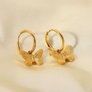 Macro shot of 18K gold-plated butterfly earrings with detailed wings on silk fabric