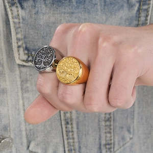 Vintage gold and silver tree of life stainless steel signet rings on denim background