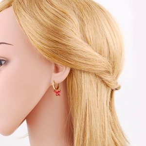Detail of red zircon butterfly charm dangling from golden hoop earring on model