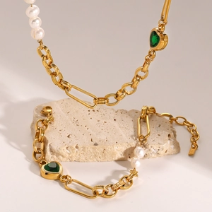 Detail of gold necklace and bracelet set with pearls and green heart pendants