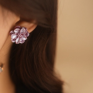 Gros plan d'un mannequin portant des boucles d'oreilles fleurs en résine violette