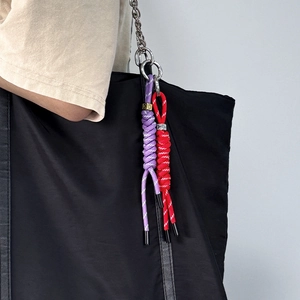 Detail of colorful braided nylon rope pendants on a black bag with metal rings
