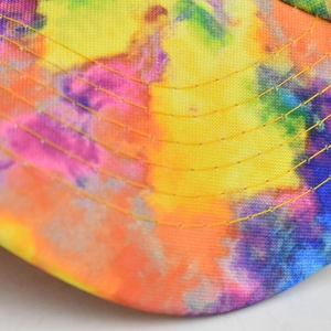 Dettaglio macro della tesa del cappellino tie-dye multicolore con cuciture gialle