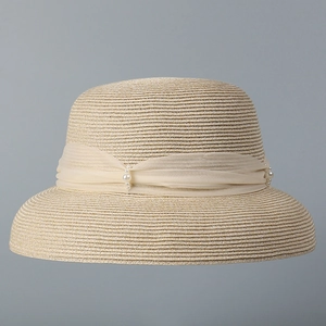 Dettaglio della trama in paglia e fiocco in chiffon con perle su un cappello estivo