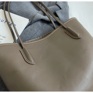 Detailed view of brown PU leather tote bag on grey blazer with professional stitching