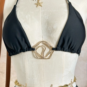 Detail of black halter bikini top featuring a central gold geometric metal buckle