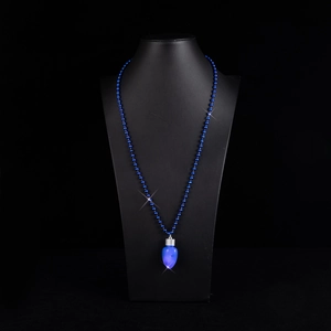 Dettaglio di un ciondolo a lampadina LED blu su una collana di perline abbinata su un busto