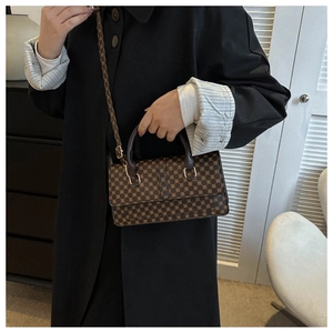 Detailed view of brown printed crossbody bag with golden hardware and top handles