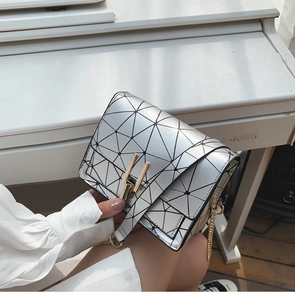 Detail of silver geometric triangle handbag with gold chain strap and metal clasp