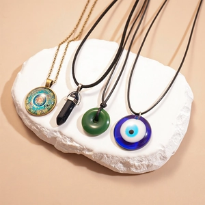Gros plan sur quatre colliers vintage avec œil protecteur, mandala et pendentifs verts