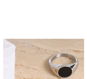 Minimalist silver ring with black round inlay on beige marble textured background