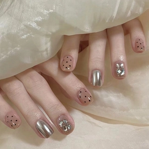 Short nude press-on nails with silver mirror finish, black dots and glitter accents
