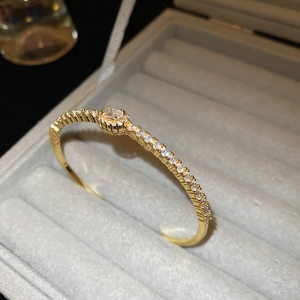 Macro shot of gold plated oval bangle with inlaid white zircons in a jewelry box