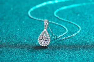 Macro shot of a silver teardrop moissanite pendant on a sparkling blue background