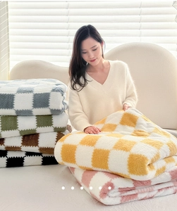 Close-up of checkered plush blankets showing soft texture and multiple color options