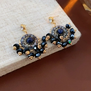 Dettaglio degli orecchini vintage con pietra blu profondo e nappe di perline nere
