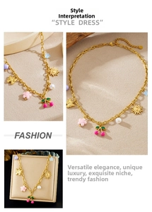 Detailed shot of gold necklace with cherry, sun, butterfly, and pearl floral pendants