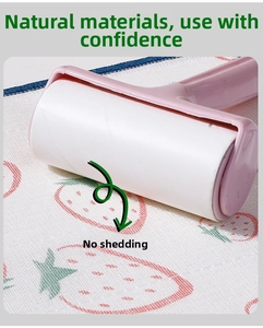 Close-up of pink manual lint roller removing debris from strawberry pattern fabric