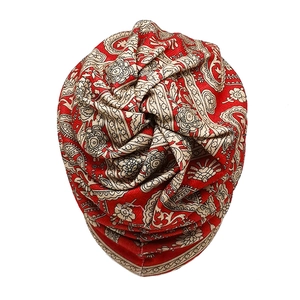 Detail of red paisley turban hat with twisted top knot and ethnic floral pattern