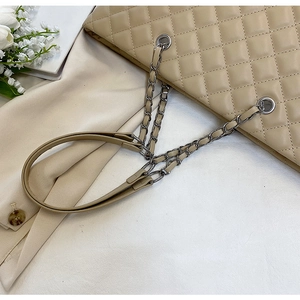 Macro view of beige quilted PU leather bag with silver chain strap and metal eyelets