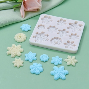 White silicone snowflake mold for DIY baking and cake decorating on green background