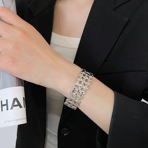Close-up of a wide silver woven metal cuff bracelet with intricate mesh texture on a wrist