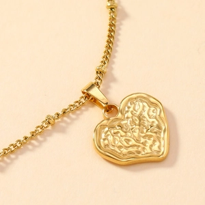 Macro shot of gold-plated heart pendant with unique textured surface on a fine chain