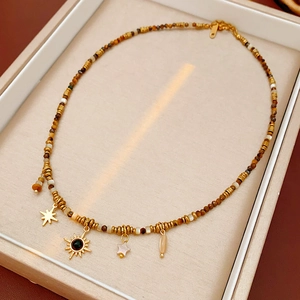 Detail of bohemian tiger eye beaded necklace with sun and star pendants in jewelry box