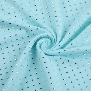 Macro shot of mint blue knit fabric with shimmering silver sequins and fine textures