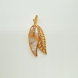 Detailed view of 18K gold-plated brooch with shell inlay and leaf design with crystals