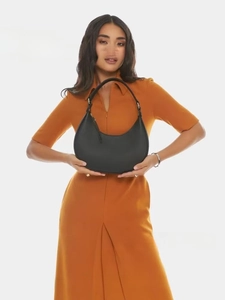 Model showcasing a black vegan leather half-moon shoulder bag with a metal zipper