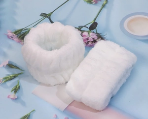 Close-up of white plush flannel wristbands for washing face on a light blue floral background