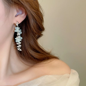 Close-up of light green floral tassel drop earrings with crystals worn on model