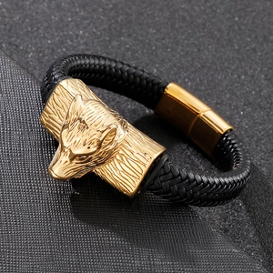 Macro view of gold wolf head carving on black braided leather bracelet with magnetic clasp