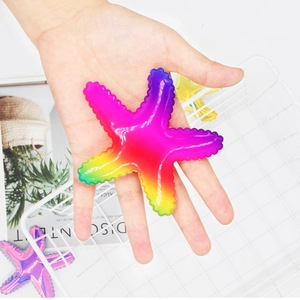 Rainbow starfish hair clip with glossy gradient finish held by hand against decor