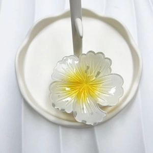 Detail of a transparent resin flower hair claw with yellow pistil on a white tray