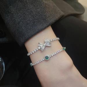 Detail of silver bow bracelet with cubic zirconia and emerald green stone tennis chain