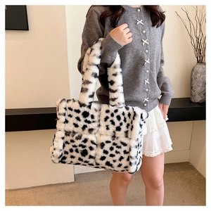 Detail shot of black and white cow print plush tote bag held by a model in a minimal setting